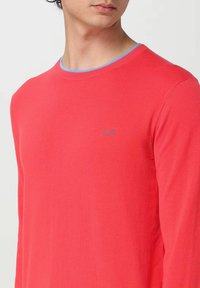 Maglione lavorato a maglia rosso a maniche lunghe con colletto a girocollo azzurro. Presenta un logo blu discreto sul petto e polsini e orlo a coste.