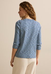 Blå- och vitrandig långärmad topp med en texturerad yta och båtformad halsringning, med trekvartslånga ärmar och en avslappnad passform.