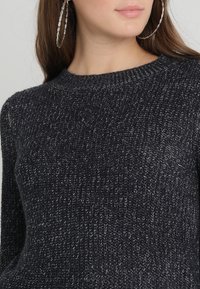 Dunkelgrauer gestrickter Pullover mit strukturiertem Muster, runder Ausschnitt und langen Ärmeln, aus einem weichen, mittelschweren Garn gefertigt.