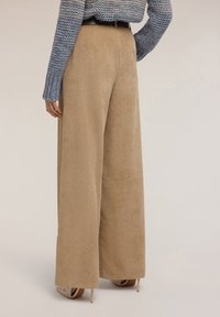 Szerokie spodnie sztruksowe w jasnobeżowym kolorze, ozdobione pionowymi prążkami. Połączone z niebieskim dzianinowym topem i paskiem w talii.