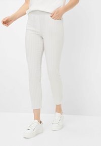 Hellgraue, gestreifte Hose mit tailliertem Design, seitlichen Taschen und schmal zulaufendem Bein. Kombiniert mit weißen Sneakers. Strukturiertes Gewebe.