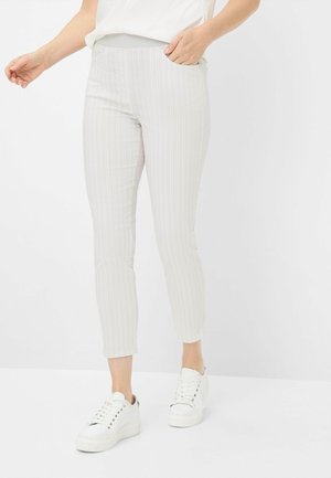 Pantaloni a righe grigio chiaro con un design aderente, tasche laterali e gamba affusolata. Abbinati a sneaker bianche. Tessuto testurizzato.