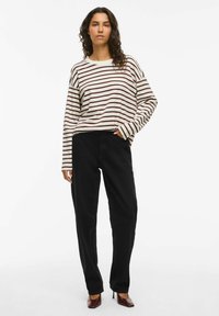 Langermet stripet topp i kremfarge og burgunder, med løs passform; kombinert med svarte vide bukser og brune hæler. Minimalistisk design.