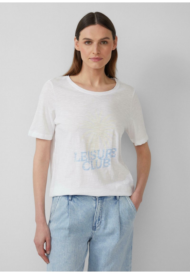 T-shirt blanc à manches courtes en tissu léger, arborant un imprimé graphique bleu décoloré avec le texte "LEISURE CLUB" sur le devant.