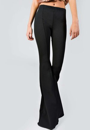 Pantalones de campana negros, confeccionados en una tela suave y elástica, con una cintura ajustada y detalles en las costuras laterales para un aspecto estilizado.