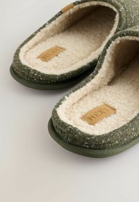 Grønne glid på slippers med en struktureret vævet overflade og fluffy beige foring. Har et lædermærke med "NEXT" logo.