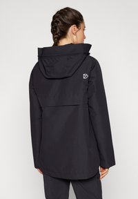 Czarna wodoodporna kurtka z kapturem, posiadająca tylną klapę i tłoczone logo. Wykonana z teksturowanej, lekkiej tkaniny.