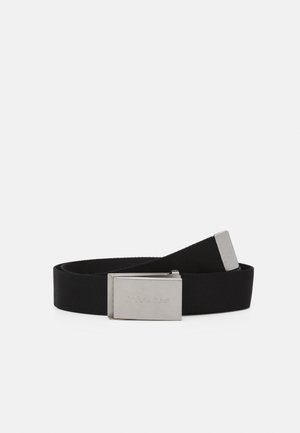 Ceinture en tissu noir avec boucle rectangulaire en métal argenté gravée de "Dickies", enroulée sur fond blanc.