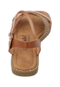 Braune Sandale mit einem strukturierten Fußbett, verstellbarem Riemen mit goldfarbener Hardware, geflochtenen Details an den Riemen und einer flachen Sohle.