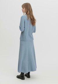 Hellblaue Strickjacke und passender gerippter Rock. Das Outfit zeichnet sich durch eine lockere Passform, strukturierten Stoff und einen knöchellangen Schnitt aus.