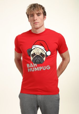 Rød bomuld t-shirt med et stort grafik af en pug iført en juleskæf, og teksten "BAH HUM PUG" i grå. Tætsiddende design, korte ærmer.