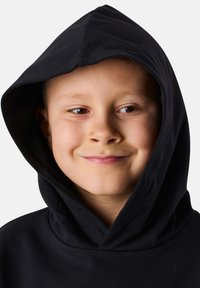 Hoodie in cotone nero con un ampio cappuccio, caratterizzato da una texture liscia e un design minimale. Il tessuto appare morbido e confortevole.