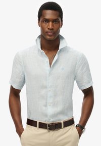Lichtblauw overhemd met korte mouwen, gemaakt van textuurstof, met een knoopsluiting en een klein geborduurd logo op de borst.