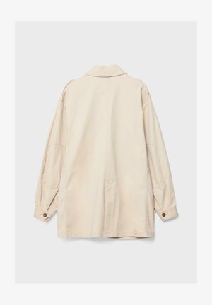 Giacca beige a maniche lunghe con polsini con bottoni, toppe sui gomiti e vestibilità comoda, vista da dietro su uno sfondo semplice.