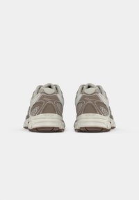 Trail running shoes with a grey-brown mesh upper, white accents, padded collar, and a thick rubber sole with textured grip.