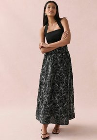 Must mustriga maksikleid musta värviga, millel on lilleline tikand, keha soe särk ja voogav seelik. Materjal tundub kerge ja pehme tekstuuriga.