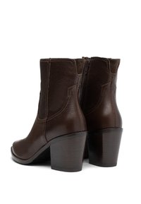 Botine de piele maro, cu fermoar lateral, cu un gât scurt și tocuri înălțate. Prezentă accente cusute și o textură netedă.