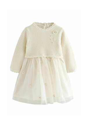 Knit cream sweater top with long sleeves, paired with a sheer cream tulle skirt featuring embroidered flower details and a ruffled hem.