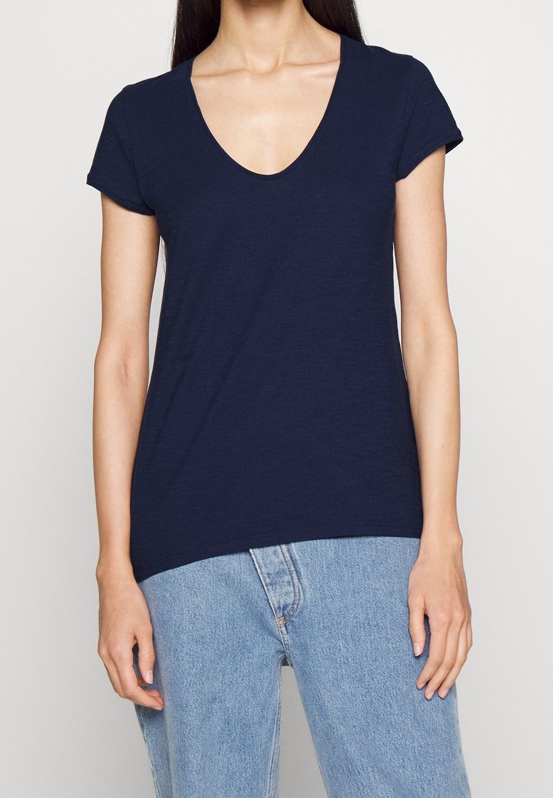 Marineblaue V-Ausschnitt-T-Shirt aus leichtem Stoff, mit kurzen, umgeschlagenen Ärmeln und lockerer Passform, kombiniert mit hochtaillierten Jeans.