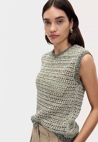 Top senza maniche in maglia color beige e nero, con motivo strutturato e scollo a coste. Il tessuto sembra leggero e traspirante.