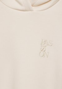 Beżowa bluza z kapturem, wykonana z miękkiego materiału, z pionowym haftowanym napisem "PASSION" w kontrastowym kremowym kolorze.