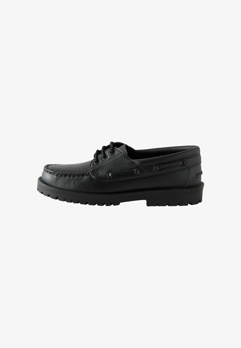 Chaussure bateau en cuir noir avec semelle épaisse en caoutchouc, devant à lacets, couture moc toe et détail de lacet sur le côté.