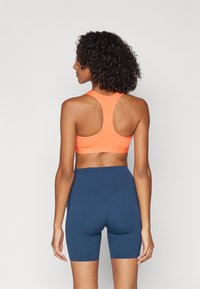 Nike Performance BRA - Vidēja atbalsta sporta krūšturis - light wild mango/white