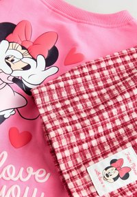 Completo di abbigliamento rosa con stampa di Minnie Mouse, fiocco rosso e cuori, abbinato a tessuto a quadretti rosso e bianco con etichetta Minnie Mouse.