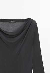 Maglietta nera a maniche lunghe con scollatura drappeggiata, realizzata in tessuto liscio. Presenta una leggera lucentezza e un'etichetta visibile all'altezza della scollatura.