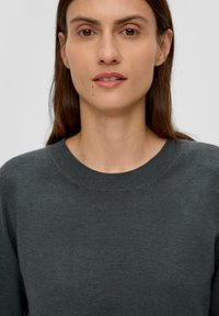 Dunkelgrauer Pullover mit Rundhalsausschnitt und langen Ärmeln, aus weichem Stoff mit glatter Textur und ohne sichtbare Muster oder Verzierungen.