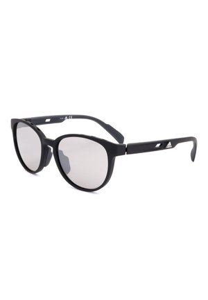 Occhiali da sole neri con montatura tonda, lenti scure e logo Adidas sulla stanghetta, mostrati su sfondo bianco.