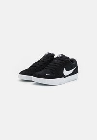 Black suede sneakers with white rubber sole and Nike swoosh logo. Features lace-up design and padded collar for comfort.