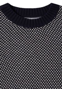 Maglione a maglia blu navy con scollatura arrotondata a costine. Presenta un motivo geometrico di piccoli cuori bianchi su tutto il tessuto.