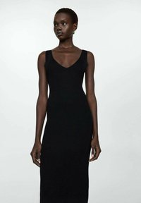 Robe en tricot côtelé noir avec un décolleté en v et sans manches. Le tissu présente une texture, offrant une silhouette ajustée.