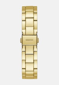 Kultainen ruostumaton teräs -kello, jossa on linkkipanta design, jossa on suorakaiteen muotoinen solki ja sileä, kiiltävä pinta. Kaiverrus lukee "GUESS."