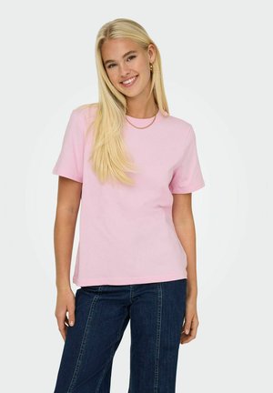 T-shirt di cotone rosa con maniche corte, scollatura rotonda e vestibilità rilassata, abbinata a jeans scuri. Design semplice, texture liscia.