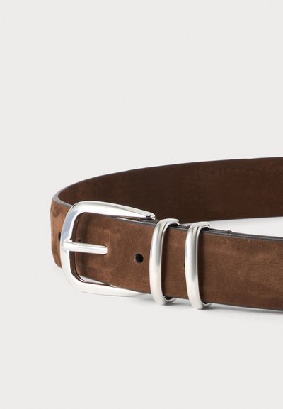 Ceinture en daim marron avec une boucle en métal argenté poli et deux passants argentés sur fond blanc.