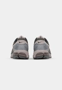Nike sportcipők szürke és bézs hálós felsőrészsel, gyémántmintás díszítéssel, párnázott bokarésszel és szilárd fekete gumitalppal.