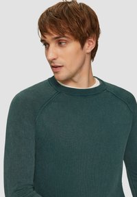 Donkergroen gebreide trui met een ronde hals en raglanmouwen. Gestructureerde stof met een subtiele, zachte afwerking.