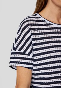 Striped top featuring navy blue and white horizontal patterns with a textured knit. Short sleeves and a round neckline.
