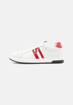 White low-top sneaker with red leather accents, red striped "S" logo on side, white laces, and black sole against a plain background.