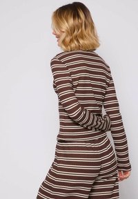 Conjunto de tela de color marrón con canalé y rayas onduladas blancas; camiseta de manga larga con una forma ajustada y cuello redondo, combinada con parte inferior a juego.