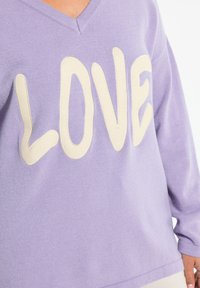 Maglione lilla con lettering "LOVE" testurizzato in crema, caratterizzato da una scollatura a V e maniche lunghe. Tessuto morbido con una vestibilità comoda.