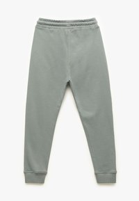 Graue Sweatpants aus Baumwollmix mit elastischem Bund, schmal zulaufenden Beinen und gerippten Bündchen. Glatte Textur und minimalistisches Design.