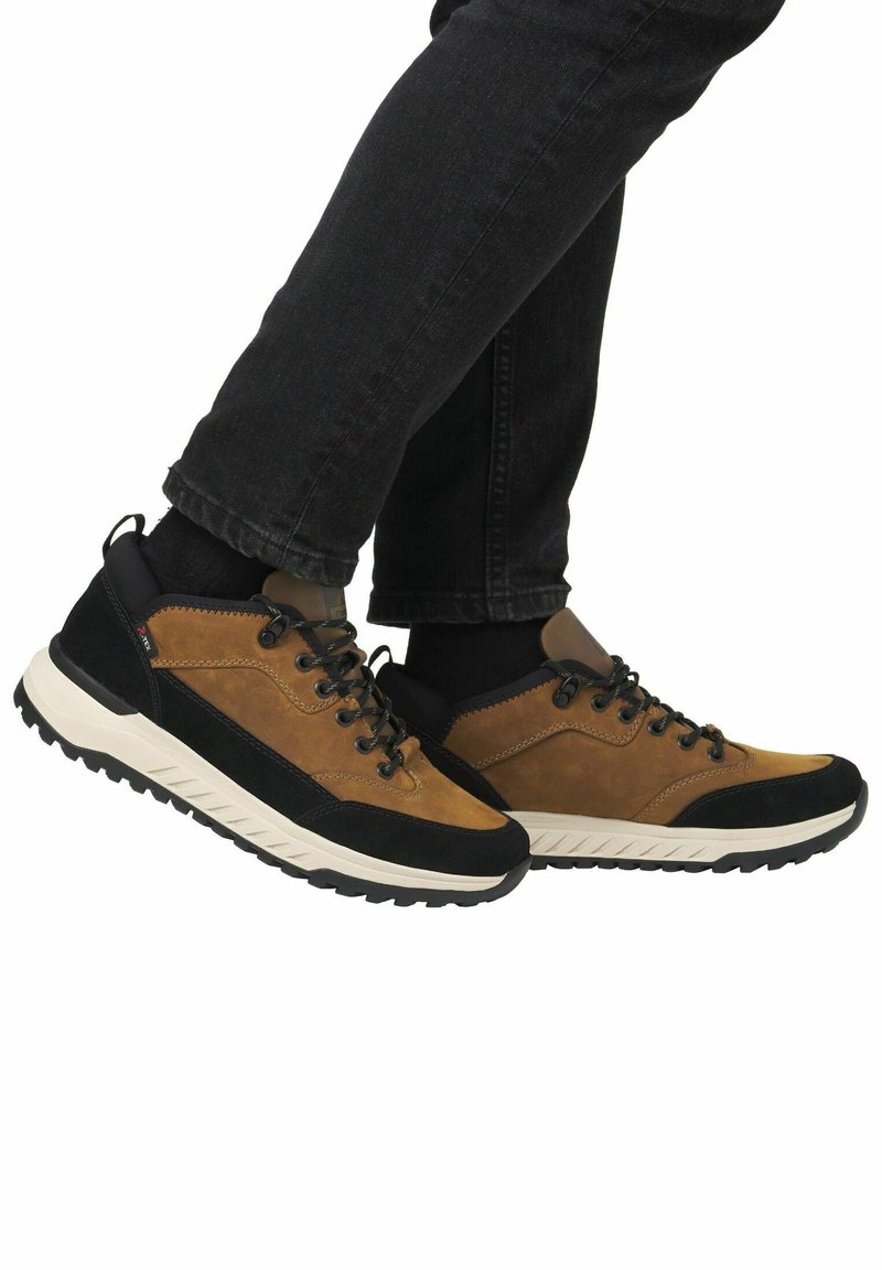 Baskets en cuir marron et noir avec des panneaux texturés, des lacets noirs et une épaisse semelle en caoutchouc blanc présentant un motif de semelle.
