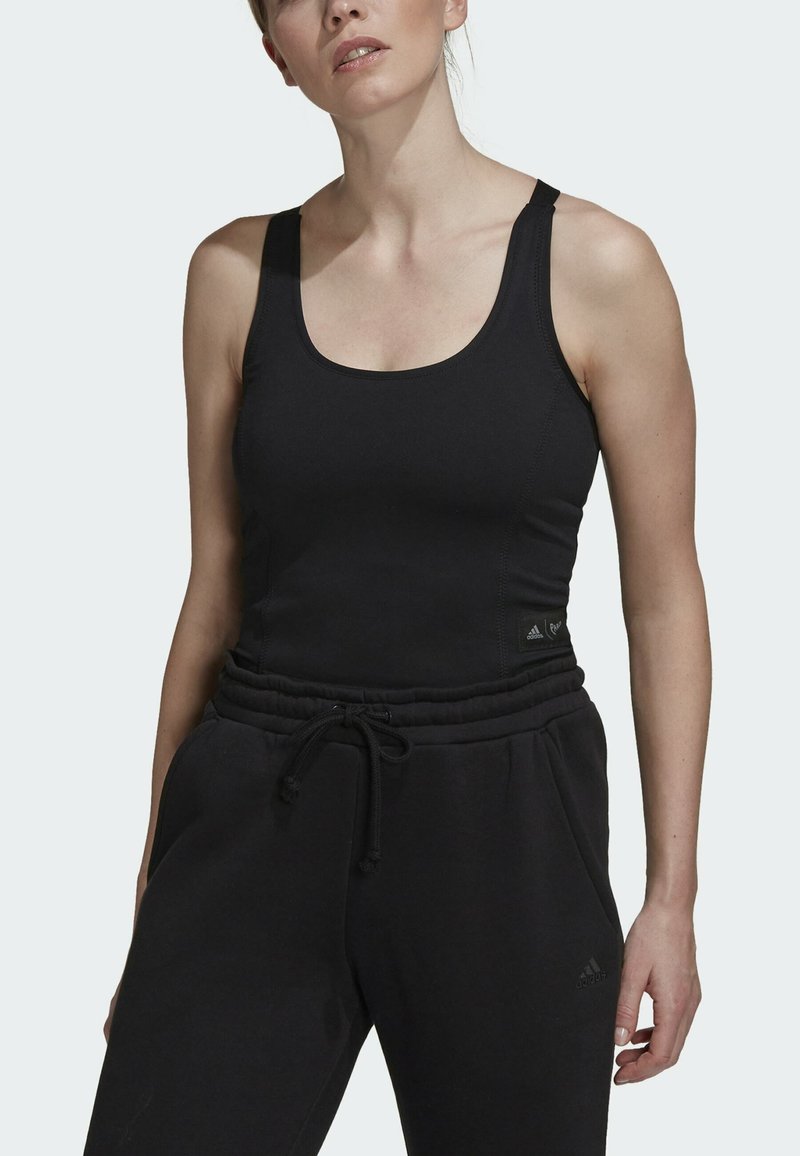 Schwarzes sportliches Tanktop mit Rundhalsausschnitt und breiten Trägern, kombiniert mit schwarzen Jogginghosen, die einen elastischen Bund und Taschen an den Seiten haben.