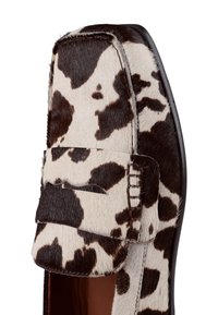 Loafer w print w krowę, z miękkim, teksturowanym futrem, prostokątnym noskiem, skórzanymi akcentami i kontrastującą czarną podeszwą. Posiada wyszywane detale.