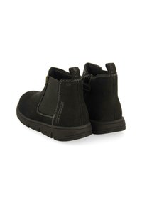 Botas de tobillo negras de ante con paneles laterales elásticos, costuras blancas finas y una suela de goma texturizada. Presenta un lazo en la parte trasera.