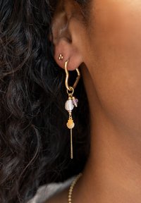 Boucle d'oreille en or avec un pendentif en forme de coquillage, des petites perles et un accent en chaîne. Surface texturée et forme organique unique.