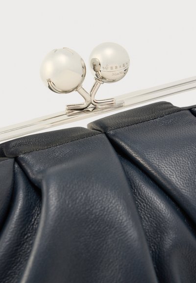 Χειροποίητο navy δερμάτινο τσαντάκι με πιετέ σχέδιο, διαθέτει ασημένιο μεταλλικό πλαίσιο και δύο στρογγυλά, μαργαριταρένια κούμπωματα στην κορυφή. Λεία υφή.